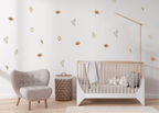 Earthy-tone leaf and flower wall decals arranged on a minimal nursery wall above a crib