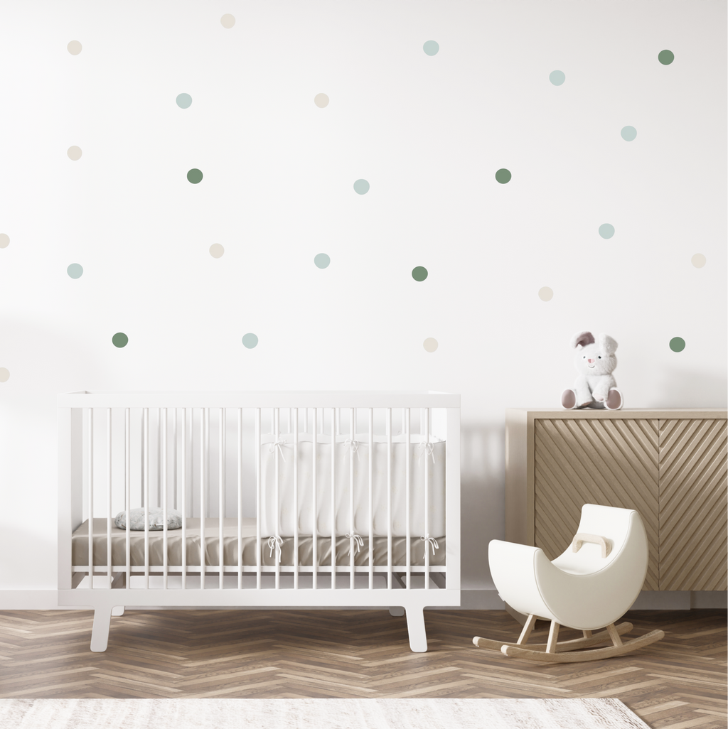Soft green and neutral dot wall decals scattered across a nursery wall above a white crib and cozy seating