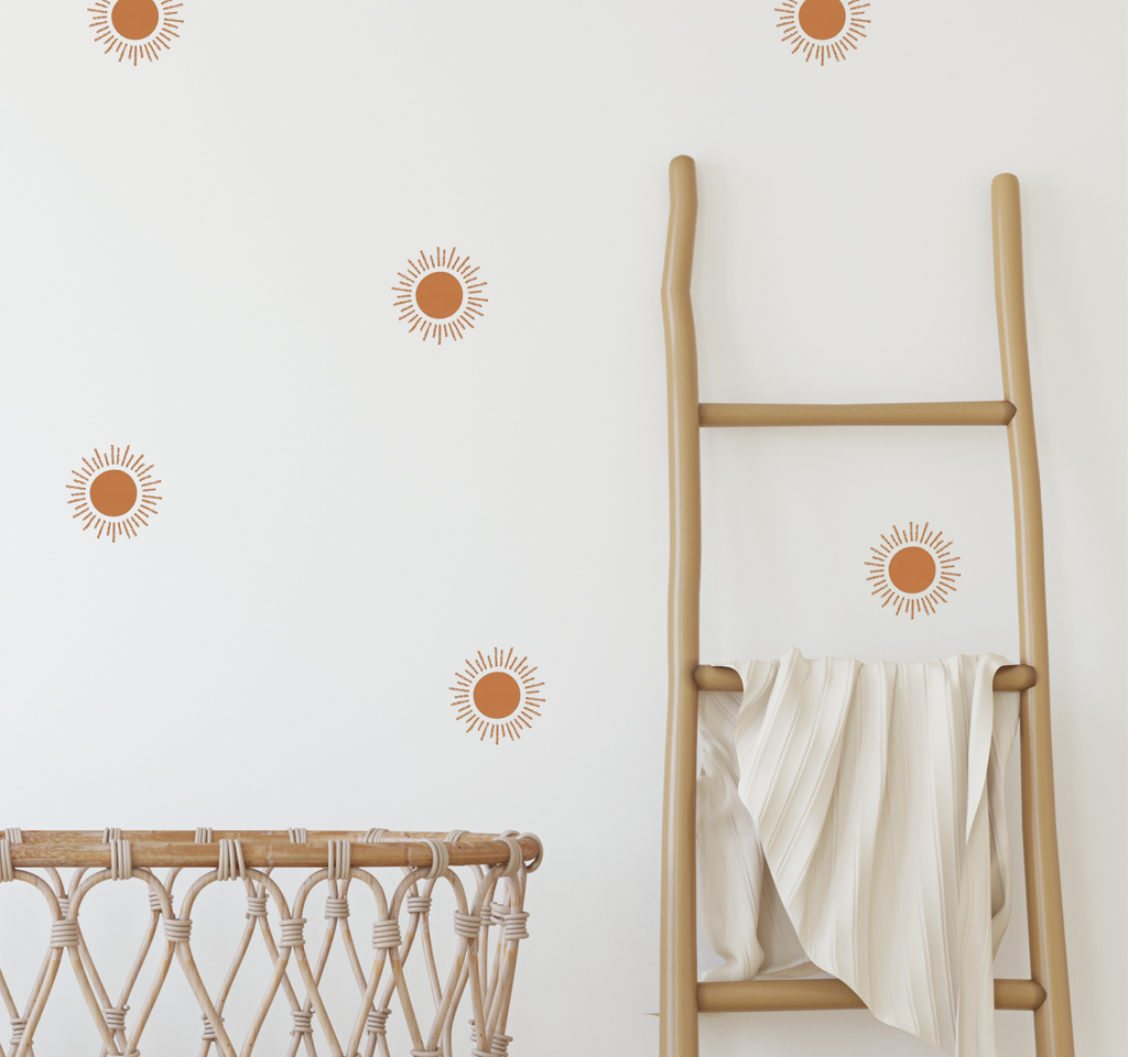 close-up of terracotta sun wall decals on a white wall next to a wooden ladder