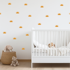 Golden sunrise wall decals scattered across a nursery wall above a white crib and soft toys
