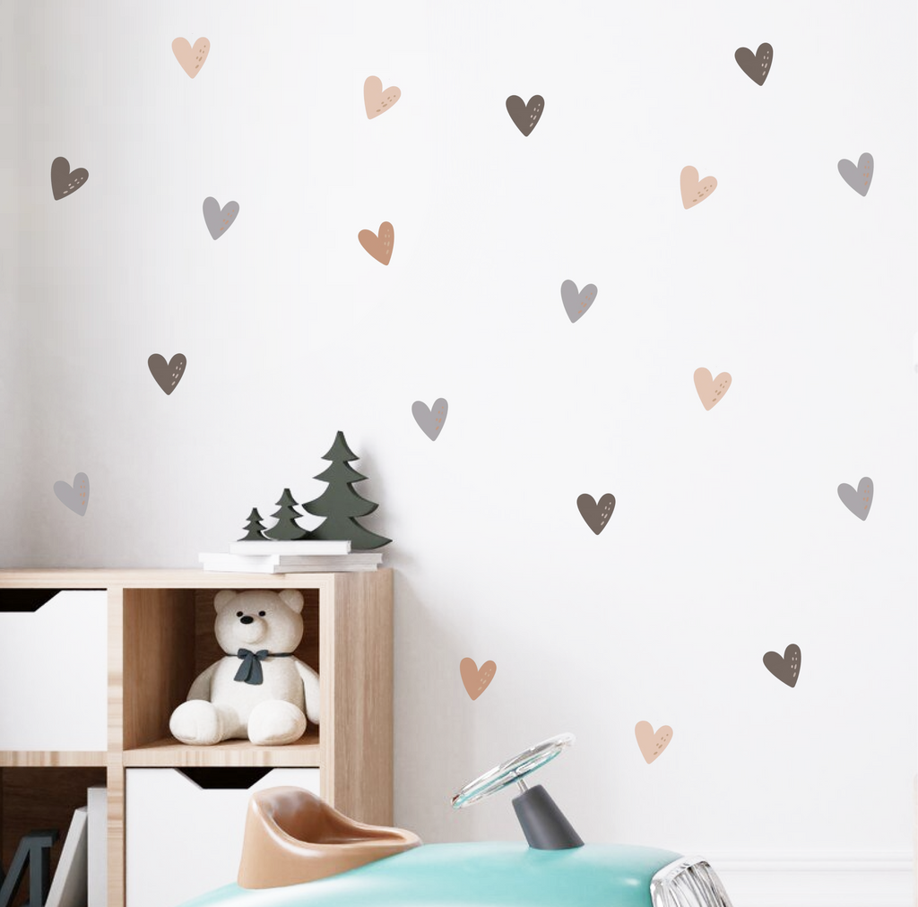 Neutral and pastel heart wall decals decorating a kids’ room behind a crib and toy car