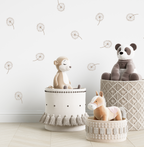 Stuffed animals in woven baskets against a white wall decorated with dandelion decals